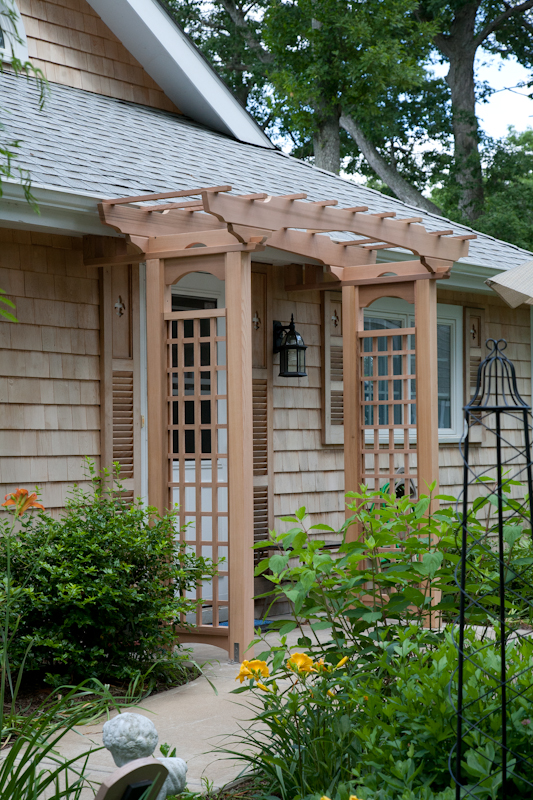 A cedar arbor with plexiglass to provide cover from the weather.