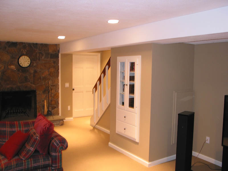 Finished basement with a fireplace and a built-in cabinet for audio equipment under the stairs in Farmington CT