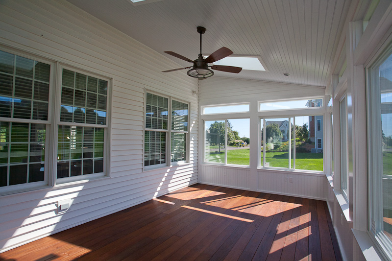 Interior of an enclosed porch built on a deck with sliding windows.